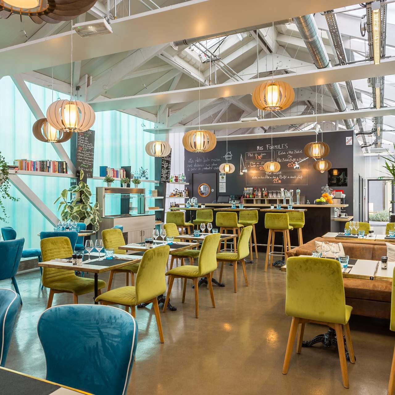 Salle à manger moderne de l'Hôtel Libéra, avec des tables élégantes et des chaises confortables, éclairage suspendu et ambiance industrielle.