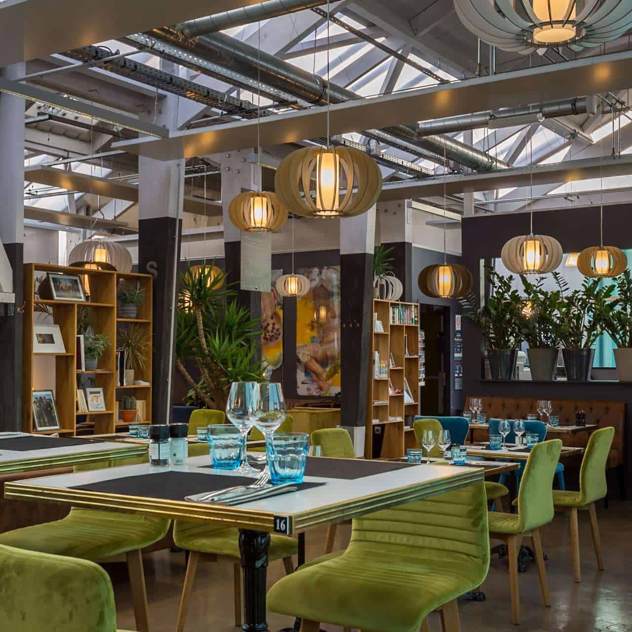 Intérieur moderne du restaurant de l'Hôtel Libéra, avec des chaises colorées et une ambiance industrielle-chic.