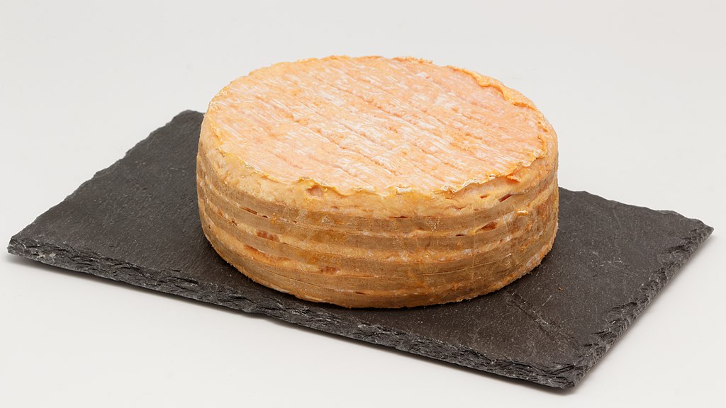 Fromage sur un plateau en ardoise, présentant une texture lisse et une croûte légèrement dorée.