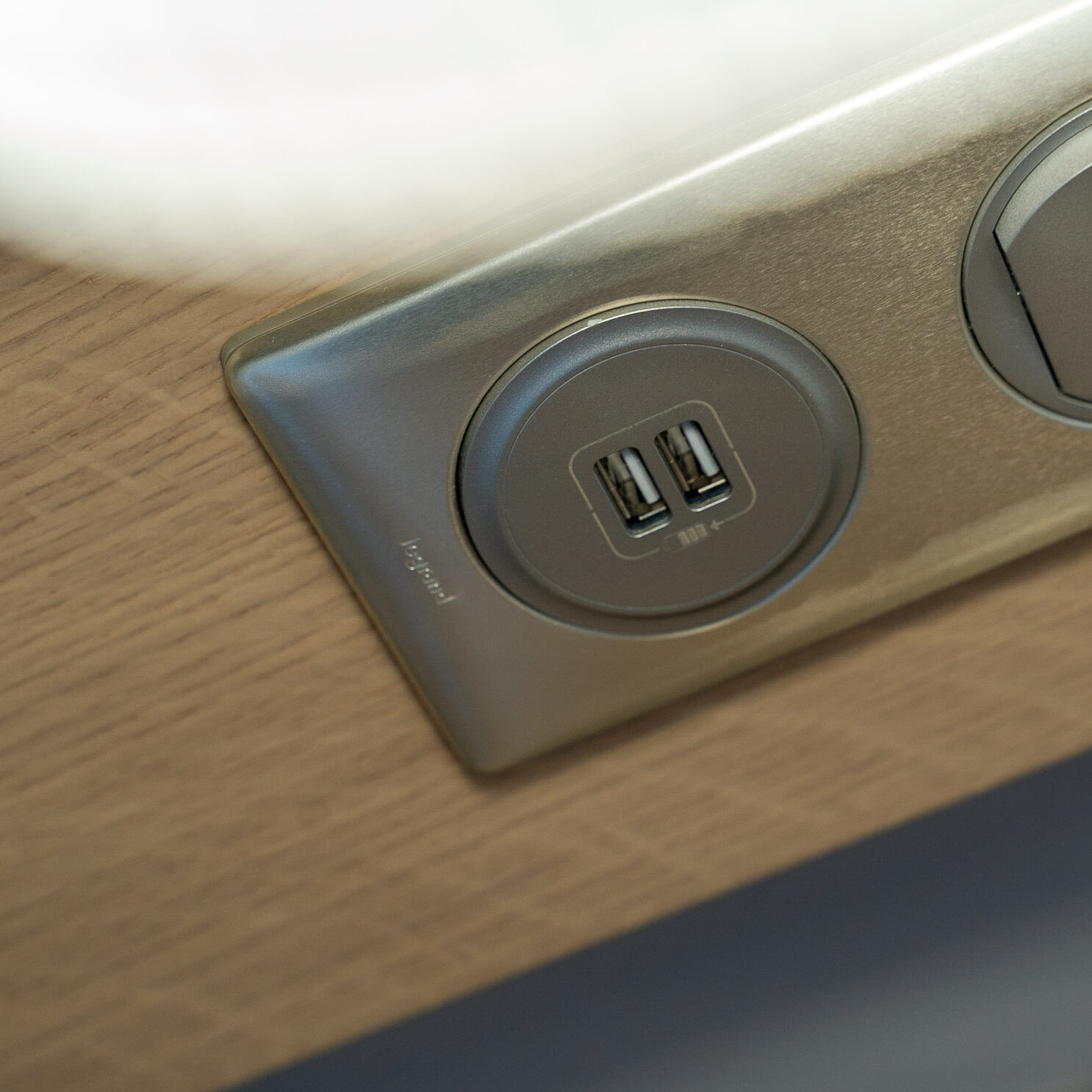 Prise électrique avec ports USB intégrés sur un meuble en bois.