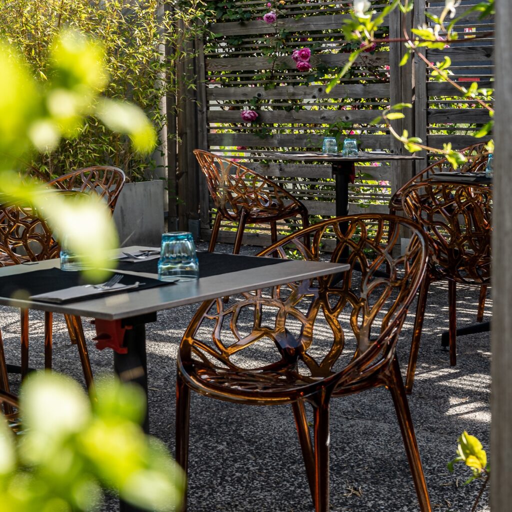 Terrasse moderne de l'Hôtel Libéra, avec des chaises élégantes et une ambiance verdoyante.