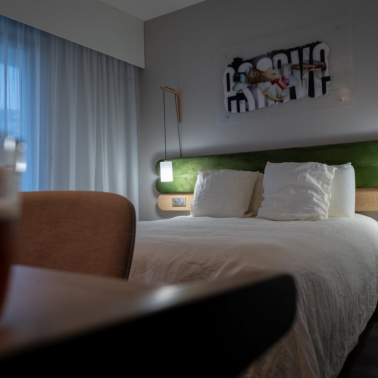 Chambre moderne et confortable de l'Hôtel Libéra, avec lit double, éclairage design et vue sur un espace lumineux.